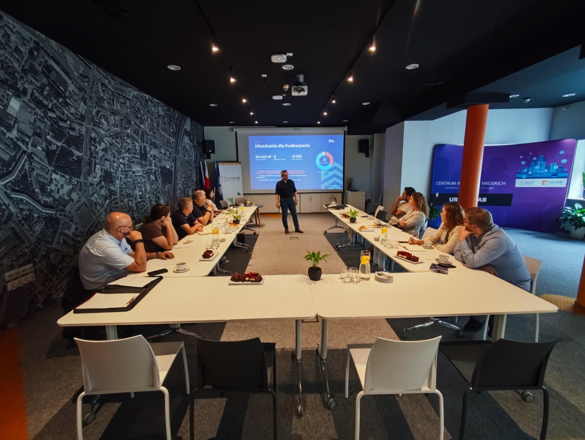 Spotkanie robocze SIM KZN Ziemi Podkarpackiej w Urban Lab Rzeszów — przedstawiciele czterech gmin przy stole konferencyjnym, na ekranie prezentacja Mieszkania dla Podkarpacia